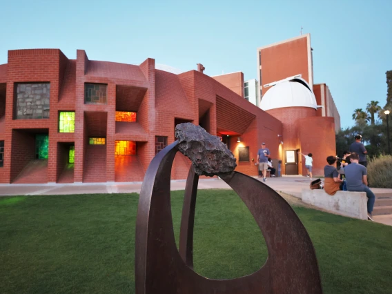 Exterior of the Flandrau Center at night with people.